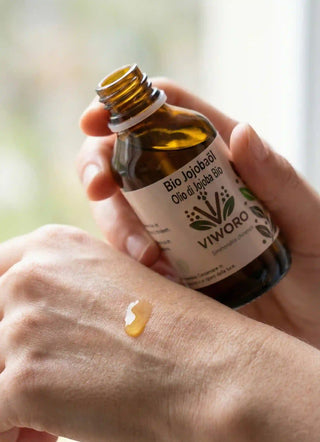 Goccia di Olio di Jojoba dorato puro sulla mano - Texture ricca e non grassa