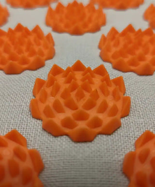 Una ripresa macro delle punte per agopressione a forma di fiore di loto arancioni sul tessuto di lino del tappetino Viworo."