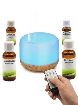 Diffusore di aromi a ultrasuoni con base effetto legno illuminato di blu, circondato da quattro 30 ml flaconcini di oli essenziali generici.
