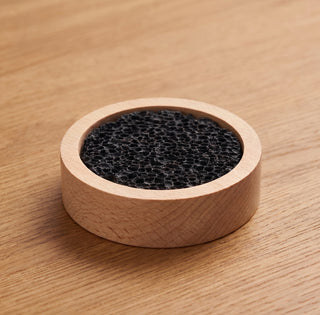 Lavastein-Diffusor: schwarzer Vulkanstein in hellem Holzring auf einem Holztisch