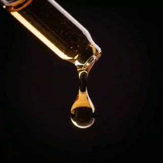 Macro di una goccia di estratto di Biancospino dal colore dorato che cade da una pipetta di vetro.