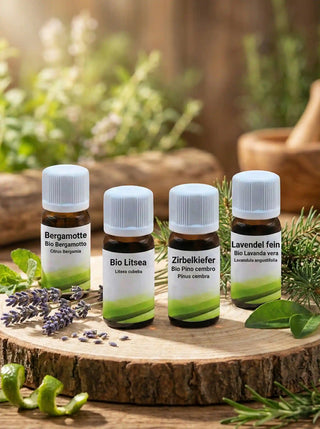 I quattro oli essenziali biologici Viworo (Zirbe, Lavanda, Bergamotto, Litsea) presentati su un disco di legno naturale con erbe botaniche.
