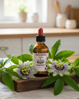 Il flacone di Estratto di Passiflora 1:1 Viworo su un tagliere di legno, circondato da foglie e fiori freschi di passiflora.