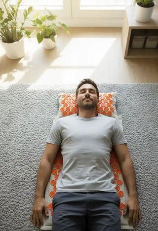 Un uomo sdraiato supino sul tappetino per agopressione Viworo in una stanza luminosa, che si gode un momento di relax.